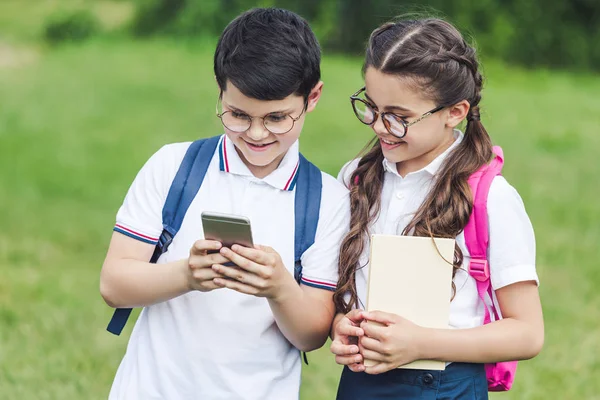Счастливые школьники используют смартфон на открытом воздухе вместе — стоковое фото