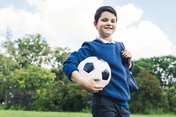 Vista inferior del niño sosteniendo pelota de fútbol en el campo de hierba - foto de stock