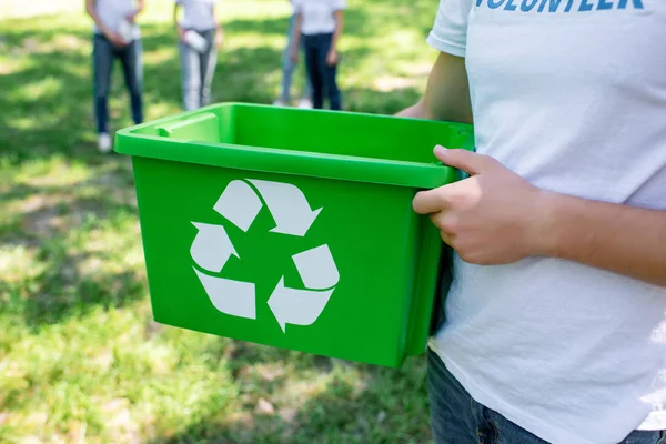 Vista cortada de voluntário segurando caixa de reciclagem verde no parque — Fotografia de Stock