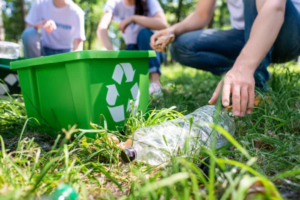 Vista recortada de los voluntarios con la caja de reciclaje de limpieza césped juntos - foto de stock