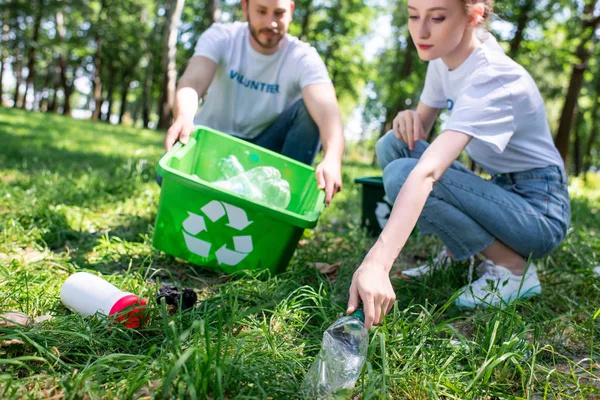 Couple de jeunes bénévoles avec boîte de recyclage nettoyage pelouse — Photo de stock