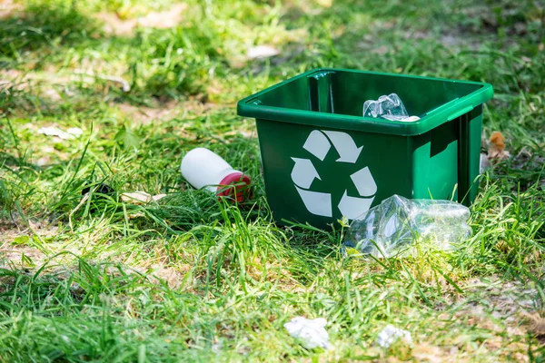 Recyclingbox und Plastikmüll auf grünem Gras — Stockfoto