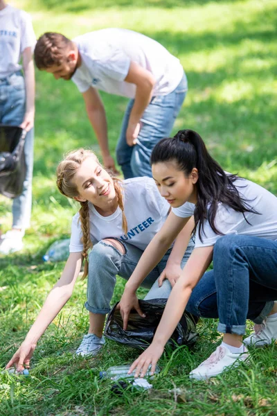 Jóvenes voluntarios felices limpieza césped verde - foto de stock