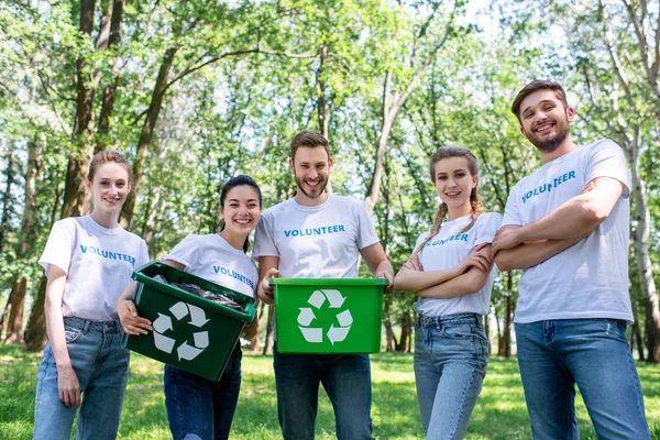 Jóvenes voluntarios con cajas de reciclaje verdes después de limpiar el parque - foto de stock