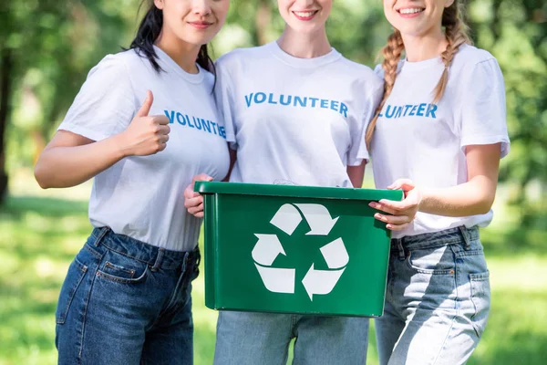 Vista cortada de jovens voluntários com caixa de reciclagem verde mostrando polegar para cima — Fotografia de Stock