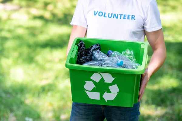 Visão parcial do voluntário masculino segurando caixa de reciclagem com resíduos de plástico — Fotografia de Stock