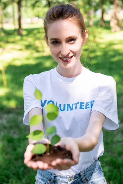 Atractivo voluntario sonriente sosteniendo nuevo en las manos - foto de stock