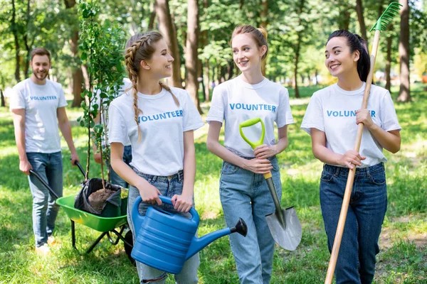 Young volunteers looking at each other in park — Stock Photo
