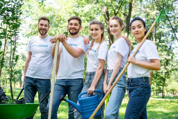 Junge Freiwillige mit Gießkanne, Schaufel und Harke im Park — Stockfoto