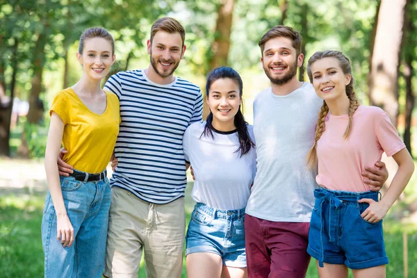 Smiling friends hugging and posing together in park — Stock Photo