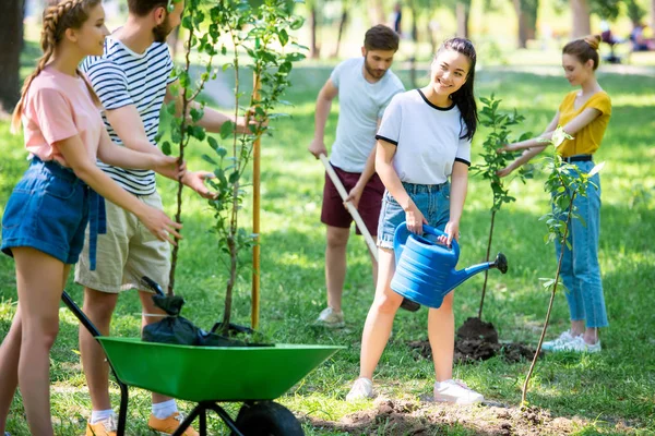 Smiling friends planting new trees and volunteering in park together — Stock Photo