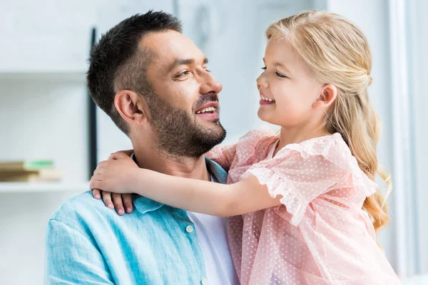 Glücklicher Vater und Tochter umarmen und lächeln sich zu Hause — Stockfoto