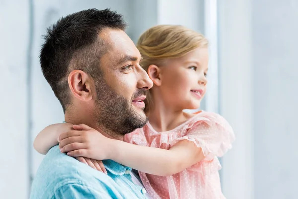 Glücklicher Vater trägt entzückende kleine Tochter und schaut zu Hause weg — Stockfoto