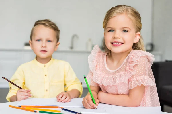 Simpatici bambini che disegnano e sorridono alla fotocamera a casa — Foto stock