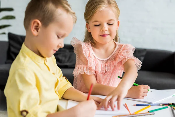 Adorables frères et sœurs dessin avec crayons de couleur à la maison — Photo de stock