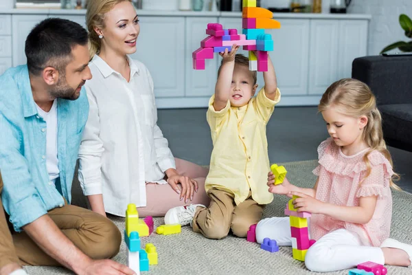 Família feliz brincando com blocos coloridos em casa — Fotografia de Stock