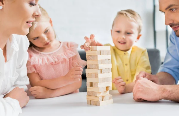 Schnappschuss von Eltern, die niedliche kleine Kinder zu Hause beim Spielen mit Holzklötzen beobachten — Stockfoto