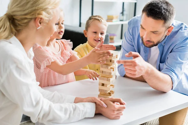 Famiglia felice con due bambini che giocano con blocchi di legno a casa — Foto stock