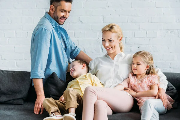Счастливая семья с двумя детьми, веселясь, сидя дома на диване — Stock Photo
