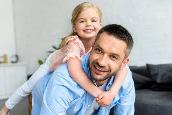 Feliz padre e hijo divirtiéndose juntos y sonriendo a la cámara en casa - foto de stock