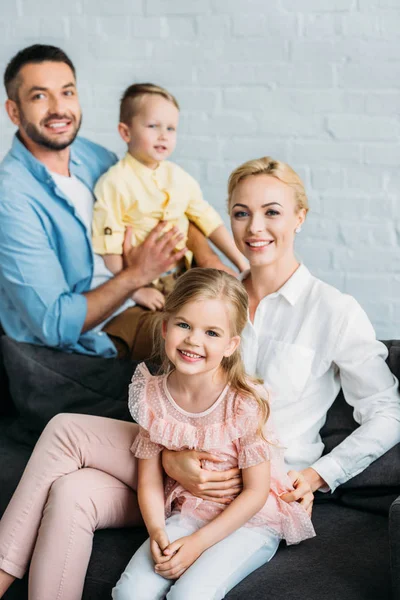 Familia feliz con dos niños adorables sonriendo a la cámara en casa - foto de stock