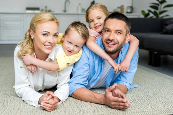 Glückliche Familie liegt auf Teppich und lächelt zu Hause in die Kamera — Stockfoto