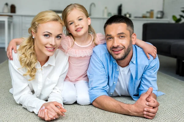 Famiglia felice con un bambino che sorride alla macchina fotografica a casa — Foto stock