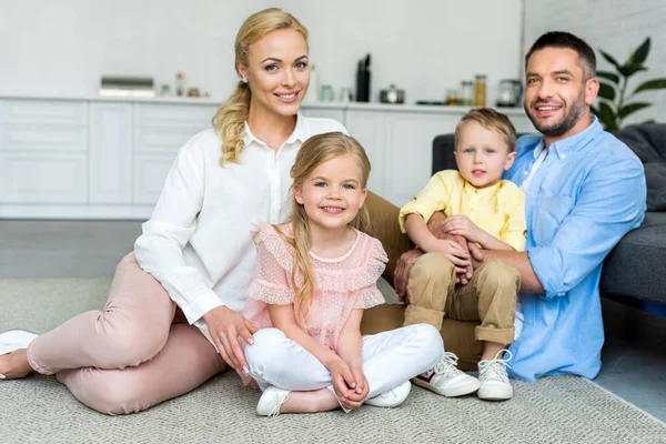 Happy family with two kids smiling at camera while sitting together at home — Stock Photo