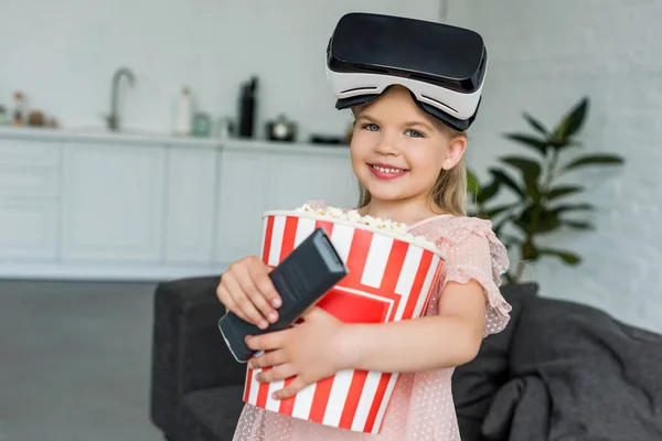 Adorabile bambino sorridente in cuffia realtà virtuale con popcorn e telecomando — Foto stock