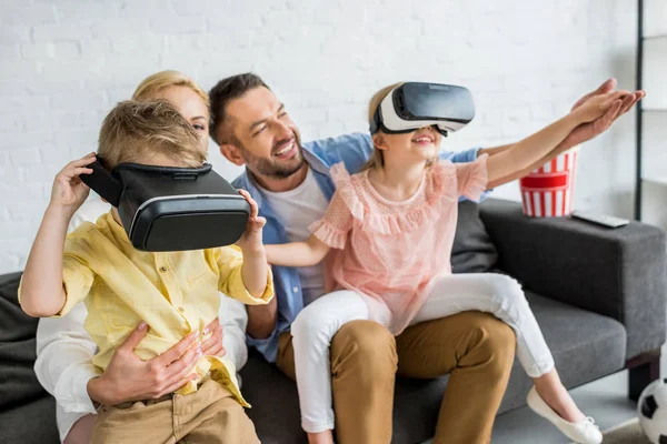 Familia feliz con dos niños usando auriculares de realidad virtual en casa - foto de stock