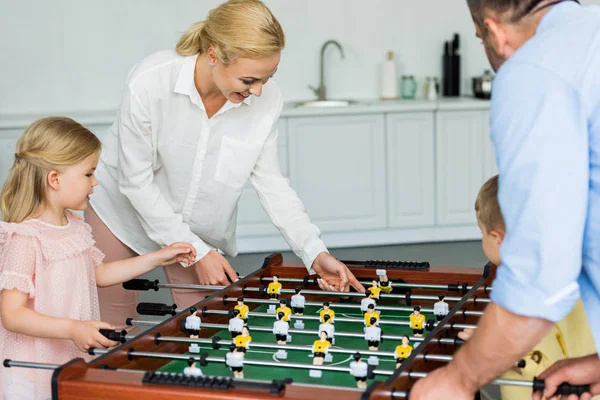 Familia feliz con dos niños jugando futbolín juntos en casa - foto de stock