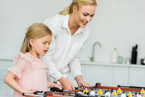 Mãe feliz e filha pequena bonito jogar futebol de mesa em casa — Fotografia de Stock