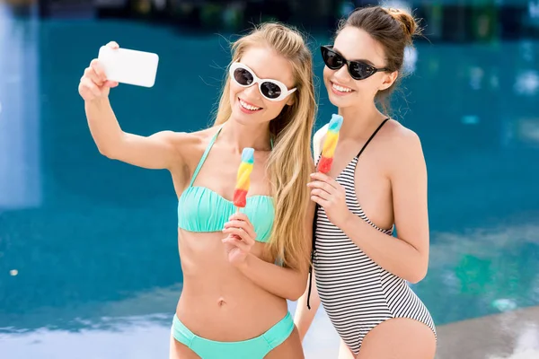 Glückliche junge Frauen in Badeanzug und Bikini machen Selfie mit Eis am Stiel am Pool — Stockfoto