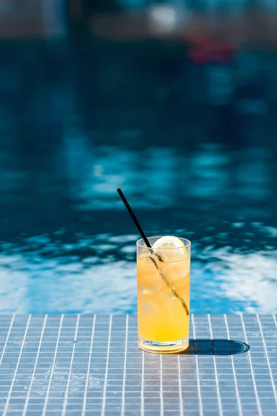 Gros plan du verre de délicieux cocktail d'orange au bord de la piscine — Photo de stock