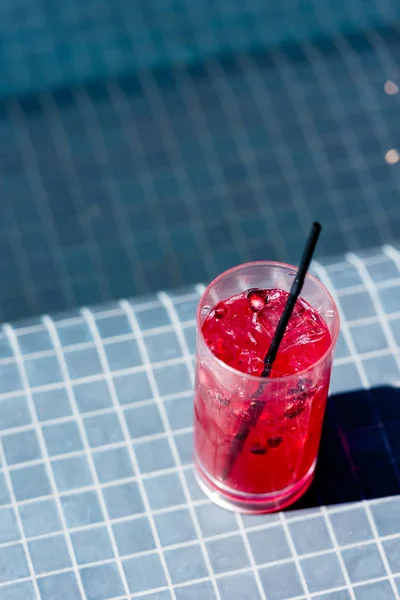 Close-up shot of glass of delicious berry cocktail on poolside — Stock Photo