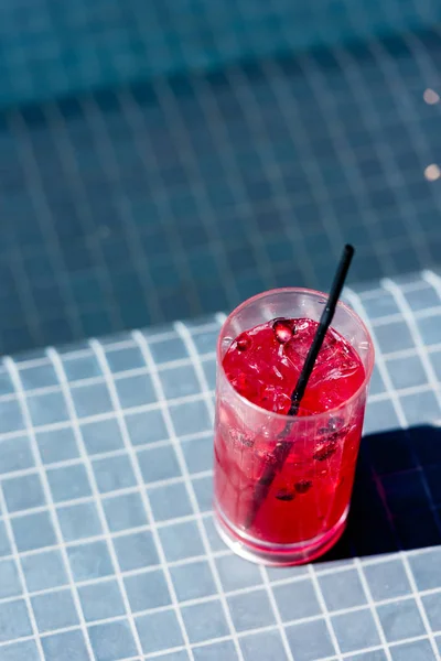 Primer plano de vaso de delicioso cóctel de bayas en la piscina - foto de stock