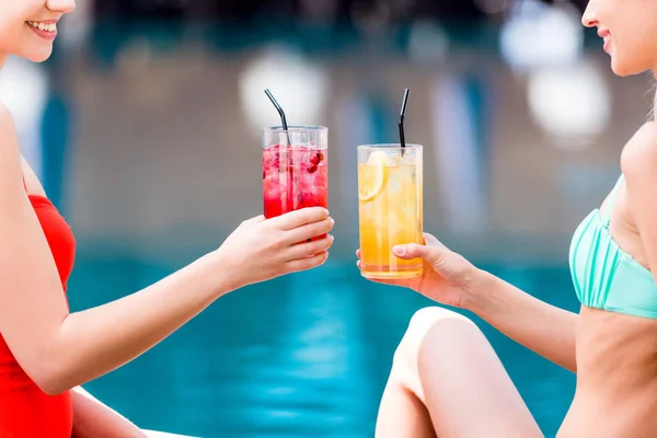 Schnappschuss von jungen Frauen, die am Pool mit Cocktails klingeln — Stockfoto