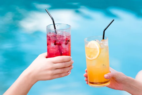 Обрізаний знімок жінок, що смердять склянки смачних коктейлів перед басейном — стокове фото