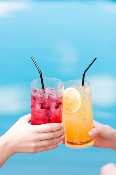 Plan recadré de femmes cliquetis verres de cocktails devant la piscine — Photo de stock