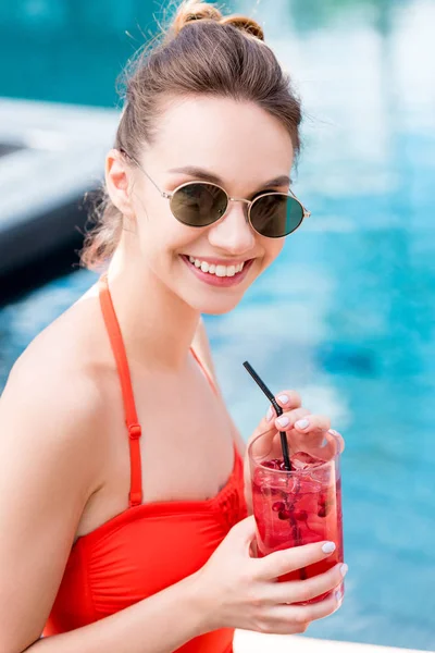Крупним планом портрет щасливої молодої жінки з ягідним коктейлем біля басейну — стокове фото