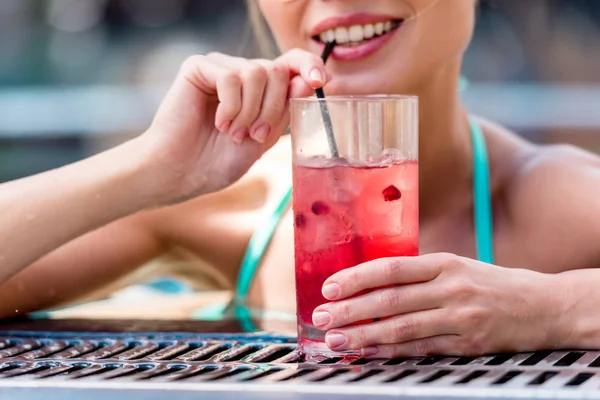 Schnappschuss einer lächelnden jungen Frau, die am Pool einen frischen Cocktail trinkt — Stockfoto