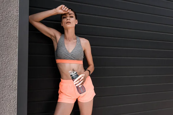 Attraktive Sportlerin posiert mit Fitness-Tracker und Wasserflasche — Stockfoto