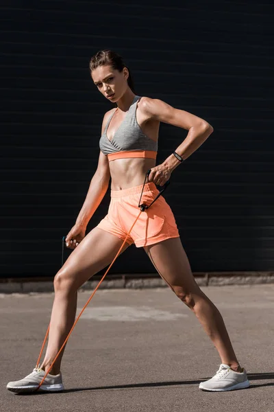 Beautiful young sportswoman stretching resistance band — Stock Photo