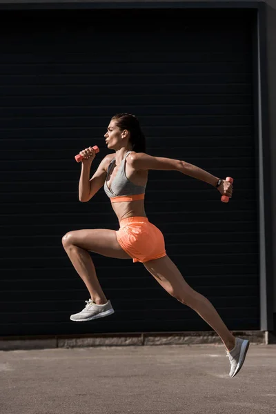 Молода приваблива спортсменка біжить з маленькими гантелями — стокове фото