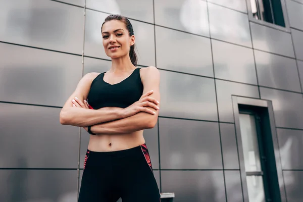 Junge Sportlerin posiert mit verschränkten Armen und blickt in die Kamera — Stockfoto