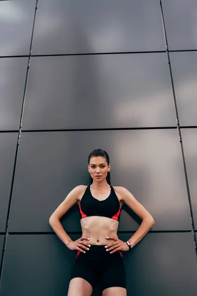 Schöne junge Sportlerin mit den Händen auf den Hüften — Stockfoto