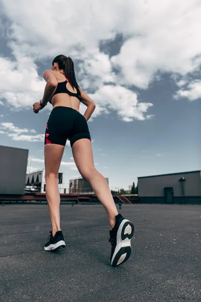 Bottom view of female jogger training on roof — Stock Photo