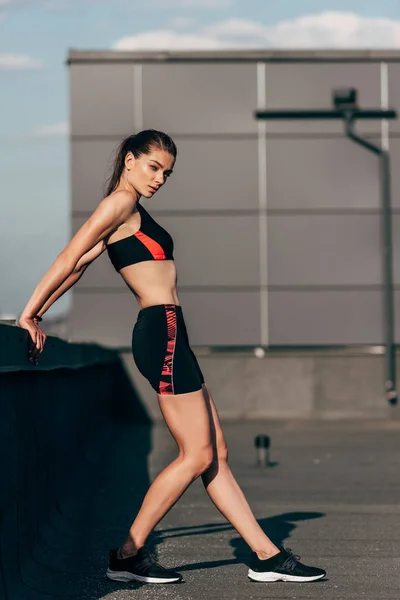 Красивая атлетическая девушка в спортивной одежде на крыше — стоковое фото