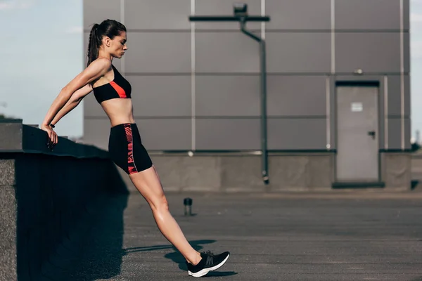 Athletic girl in sportswear doing push up on roof — Stock Photo