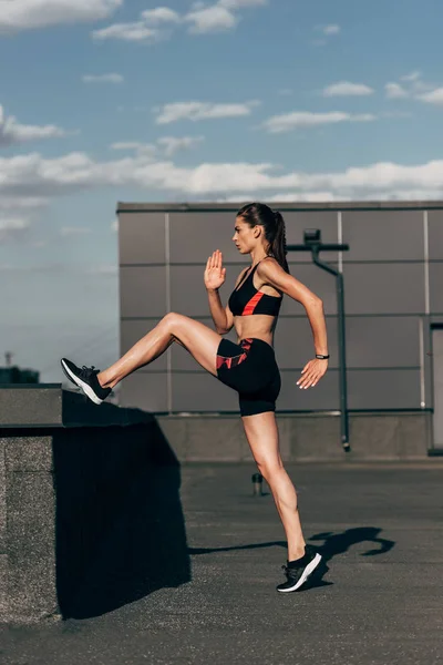 Chica atlética en ropa deportiva haciendo entrenamiento cardiovascular en el techo - foto de stock